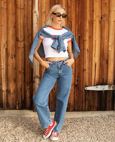 Emma Chamberlain wearing levi's baggy dad jean in front of wood wall